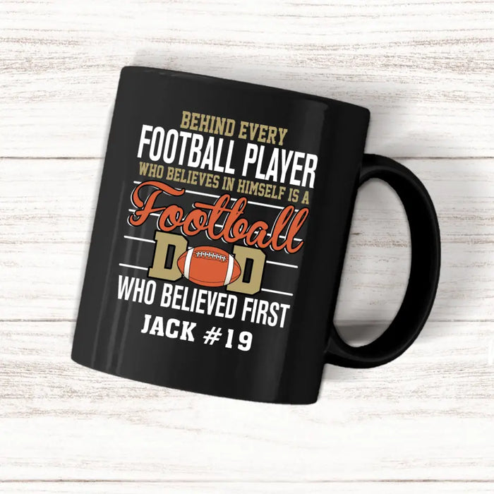 Personalized Behind Every Football Player Who Believes In Himself Is A Football Dad Who Believe First Mug, Custom Mug For Football Dad, Football Mom